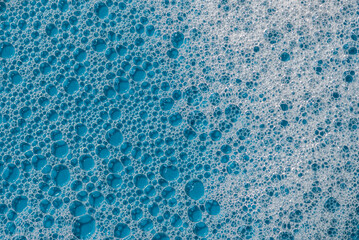 Background and pattern. White soap foam with bubbles, texture on blue tile background.