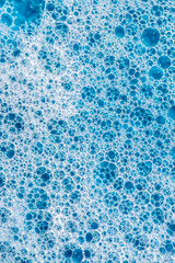 Background and pattern. White soap foam with bubbles, texture on blue tile background.