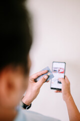 A Southeast Asian man is shopping online, using his debit card for a seamless transaction.
