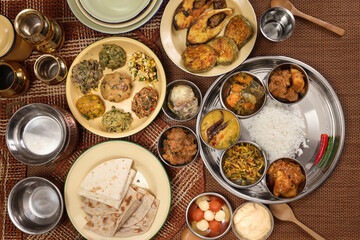 Bengali style thali spread verity cuisine hilsa fish vegetable beef mutton egg curry fry vorta mashed chicken liver sweet yogurt side dish served on rustic metal tin stainless steel plate small bowls