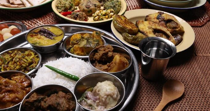 Bengali style thali spread verity cuisine hilsa fish vegetable beef mutton egg curry fry vorta mashed chicken liver sweet yogurt side dish served on rustic metal tin stainless steel plate small bowls