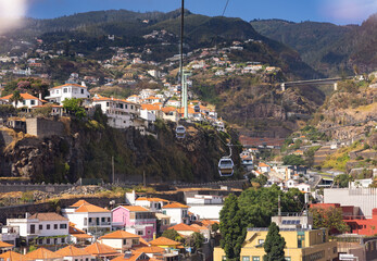 Cable car with cabins above cityscape of Funchal and Monte with the mountains in background. Madeira Island, Portugal