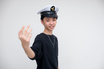 A jolly young asian man wearing a captain's hat inviting you to come along. Isolated on a white background. Party cruise themes.