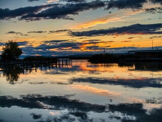 Obraz premium Sunset over tranquil lake with vibrant reflections.
