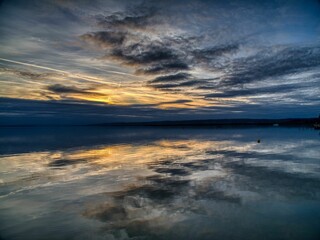Obraz premium Sunset over calm lake with reflections.