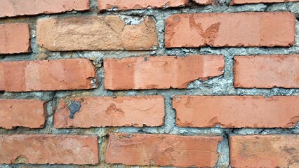 Obraz premium a close-up view of a brick wall. The bricks are reddish-orange in color and are arranged in a horizontal pattern with gray mortar in between them