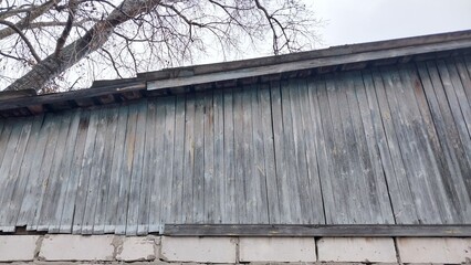 a section of a building with a corrugated metal wall. The metal appears weathered and has a grayish color. Below the metal wall, there is a row of concrete blocks forming the base of the structure