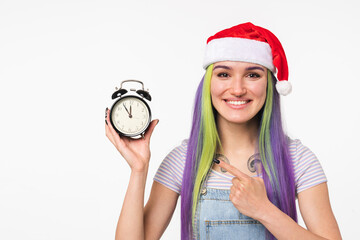 Happy young caucasian girl woman in red Santa Claus hat pointing at clock for celebration New...