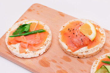 Rice Cake Sandwiches with Fresh Salmon, Cucumber, Lemon and Greens on Wooden Cutting Board. Diet Food. Quick and Healthy Sandwiches. Crispbread with Fresh Fillings. Healthy Dietary Snacks