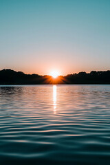 A stunning sunrise over a tranquil lake with a misty forest reflected on the water's surface