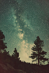  captivating retro-style landscape featuring a massive moon rising above rugged terrain, with stars illuminating the dark sky