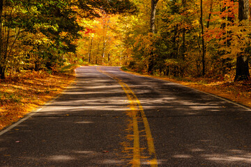 Obraz premium Highway K Rustic Road near Lost Canoe Lake, looking east,g near Boulder Junction, Wisconsin in mid-October, encased in the changing colors of autumn