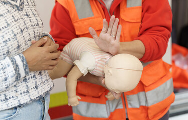 Close-up of paramedic demonstrating infant CPR on a mannequin during a training session