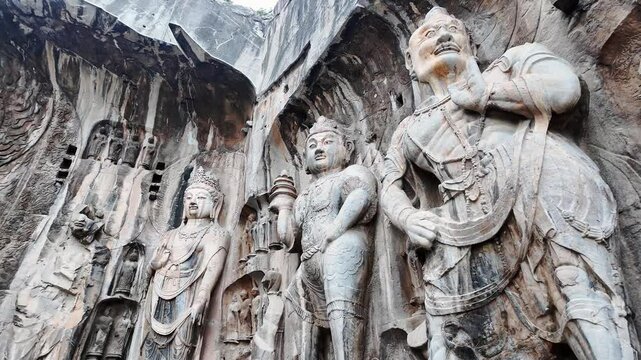 Luoyang Longmen, China: Pan footage of the famous statues and the Big Vairocana Buddha in the Longmen grottes Fengxian main cave that dates back from the 7th century in Central China.