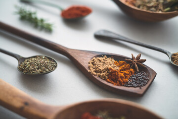 Closeup, spoon or spices in studio for cooking, recipe or healthy seasoning in Indian cuisine. Utensils, powder or ingredients on white background for spicy meal, flavor preparation or culinary skill