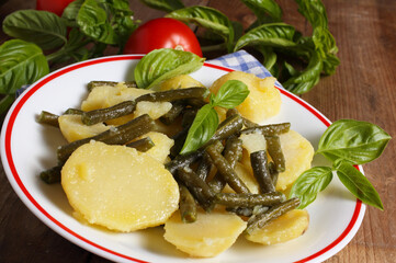 Salad of boiled potatoes and green beans with fresh basil leaves.