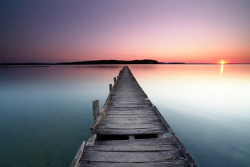 Fototapeta premium beautiful never ending wooden pier over the sea in sunrise light 