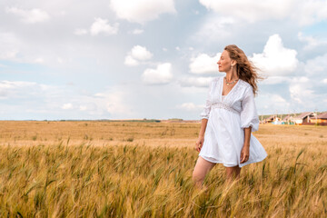 Russia, Republic of Tatarstan, Kalmash village, August 01, 2024, 17:00, girl in a dress in a wheat field in summer