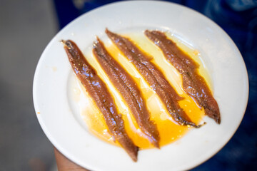 Boneless anchovies with olive oil or bonquerones, a Spanish cuisine. Popular in coastal regions like Catalonia, Andalusia, and the Basque Country. These small, silvery fish are marinated in vinegar. 