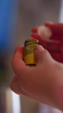 Woman opens and examine small brown bottle of poisonous powder ready to poison relative and get heritage at dinner at home closeup slow motion