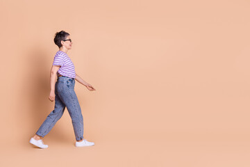 Photo of cheerful adorable retired woman wear striped trendy clothes empty space isolated on beige color background