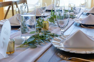 Elegant table setting with white napkins and greenery.