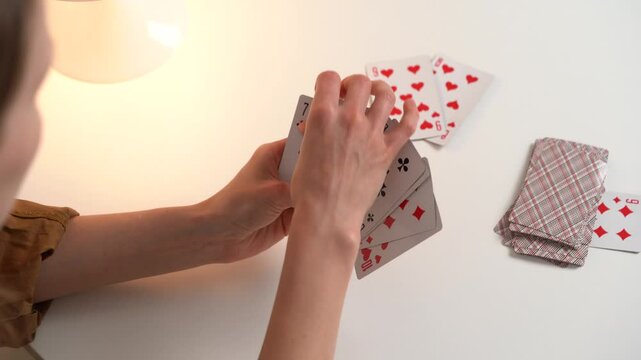 A young woman playing cards chooses how to move, looks at the trump card, and puts the card on the deck on the beach. Concept of board card games, getting fun, entertainment
