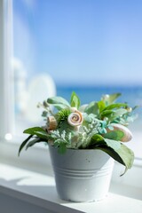 Decorative plant with seashells by ocean view window.
