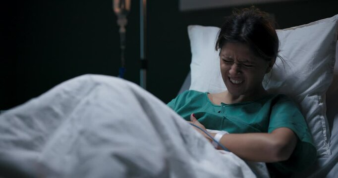 Female patient in hospital ward lying in bed suffering from gastritis.