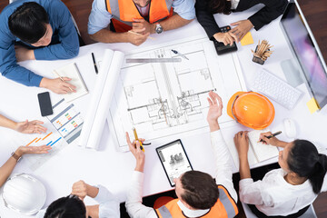 Top view banner of diverse group of civil engineer and client working together on architectural project, reviewing construction plan and building blueprint at meeting table. Prudent
