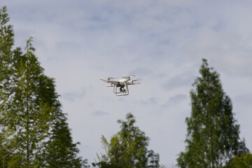 White Drone Flying in the Sky with Trees in Background
