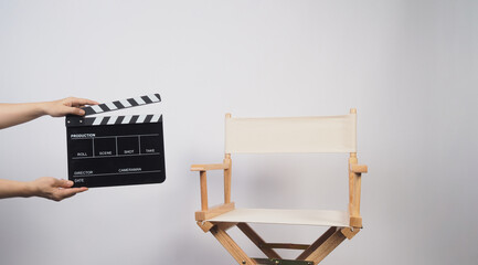 Director chair in ivory color and hand is hold clapper board on white background