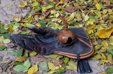 a well-worn leather falconry glove with a leather falconry hood placed on top, lying on a ground covered with yellow and green autumn leaves.