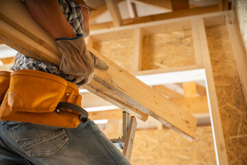 Construction Worker Carrying Wooden Beams Inside a Building Under Renovation During the Day