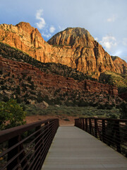 Footbridge, part of the Pa’rus trail in Zion National Park, where it crosses the Virgin River with a majestic sandstone cliff rising in the background.