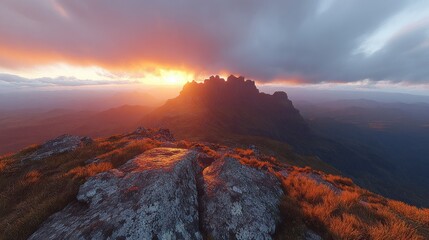 Fototapeta premium A breathtaking view of a mountain range at sunset. The sun is setting behind the mountains, casting a warm glow on the landscape. The sky is filled with colorful clouds.