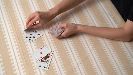 Hands of a young woman dealing classic cards from a deck for playing solitaire at a table. The concept of board card games, having fun, entertainment, poker.