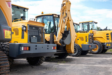 Yellow construction equipment stands in a row.