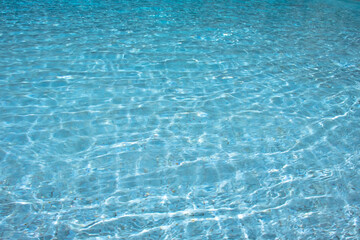Crystal clear water ripples in a swimming pool with sunlight reflections on the surface