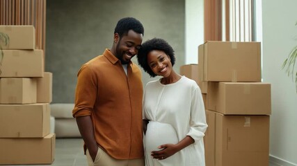 A joyful black couple stands close, celebrating their impending parenthood amidst unpacked moving boxes in their new home