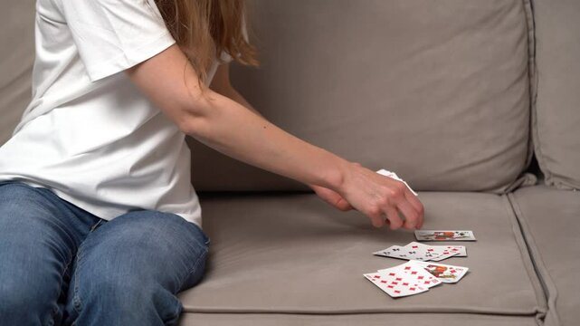 Young woman dealing classic cards from a deck for playing solitaire on the sofa. The concept of board card games, having fun, entertainment, poker.