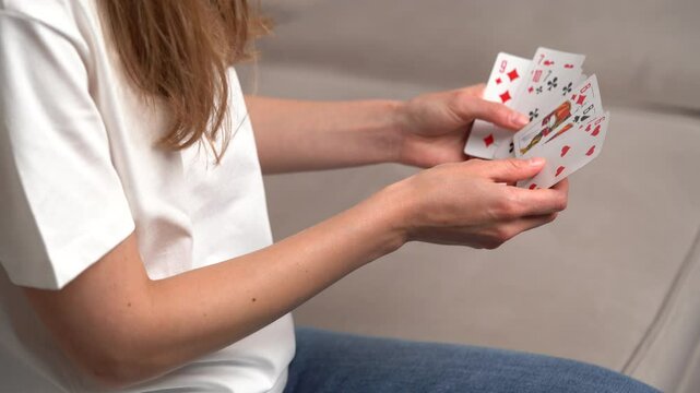 young woman's hand holding cards and choosing how to move, looking at the trump card, and placing the card on the deck at the table. Concept of board card games, getting fun, entertainment