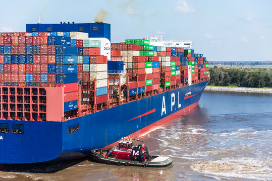 Charleston, SC, USA- Large container ship APL Sentosa, during her maneuvering on departure from container terminal in Charleston. She is fully loaded with colorful containers.