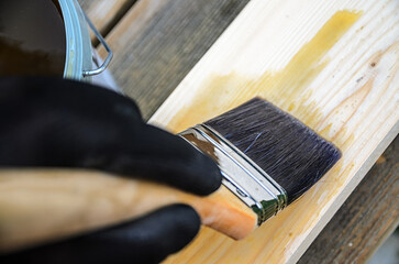 The concept of carpentry and wood preservation - painting wooden boards with linseed oil varnish.