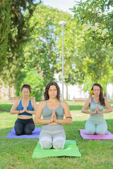 Three women meditating outdoors.