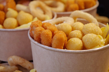 Fried potatoes, cheese fried balls and other baked goods in large paper bowls