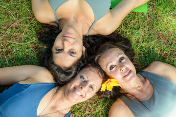 Three women lying on the grass, smiling.