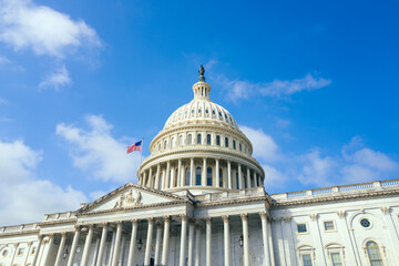 Obraz premium United States Capitol building with American flag over blue sky background, Washington DC