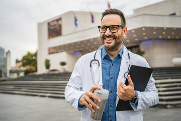 Portrait of doctor stand with clipboard and thermos on coffee break