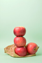 Red apples stacked on kraft paper bag. Green background and copy space.